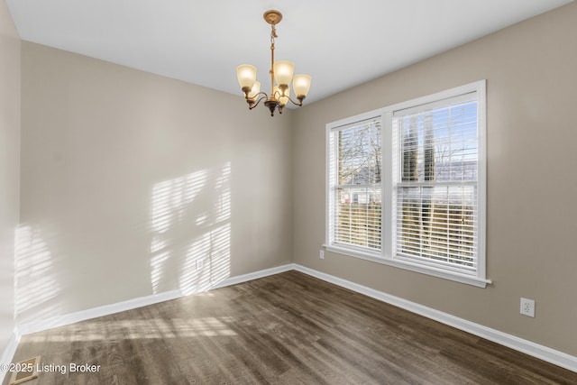 spare room featuring baseboards, a chandelier, and dark wood-type flooring