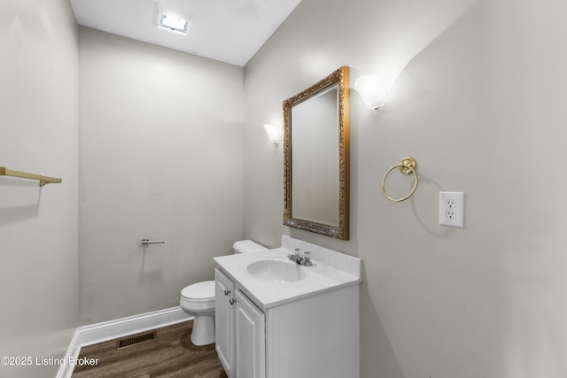 bathroom with baseboards, visible vents, toilet, wood finished floors, and vanity