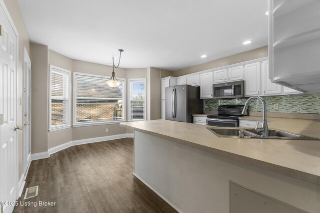 kitchen featuring decorative light fixtures, light countertops, appliances with stainless steel finishes, white cabinetry, and a sink