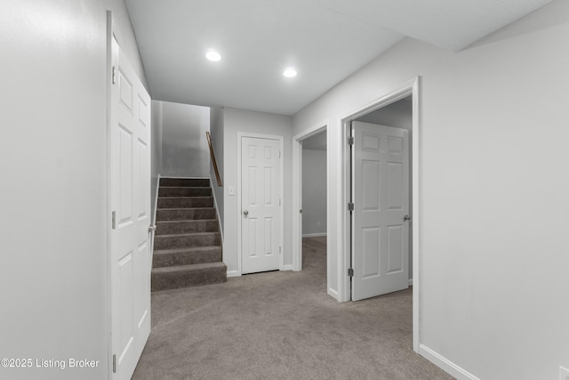 corridor with recessed lighting, light carpet, baseboards, and stairs