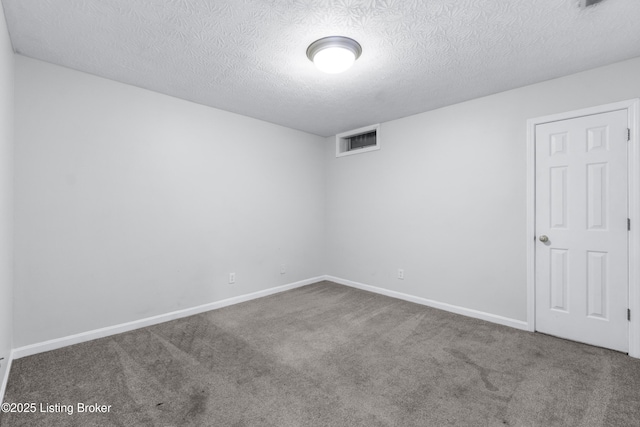 carpeted spare room with a textured ceiling, visible vents, and baseboards