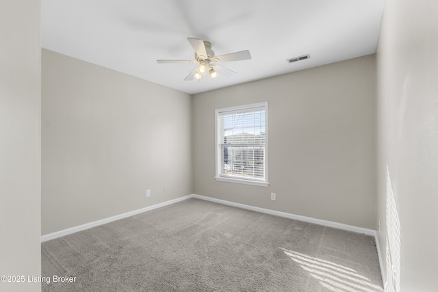 spare room featuring carpet floors, a ceiling fan, visible vents, and baseboards