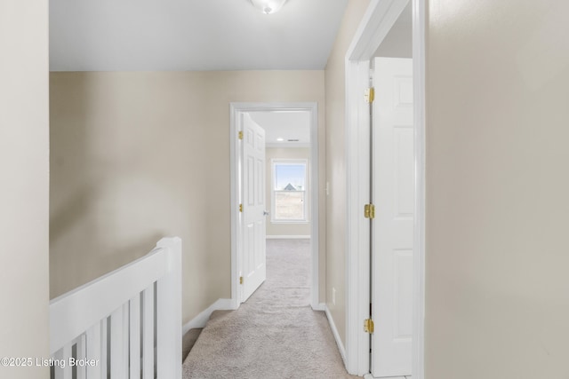 hall with light carpet, baseboards, and an upstairs landing