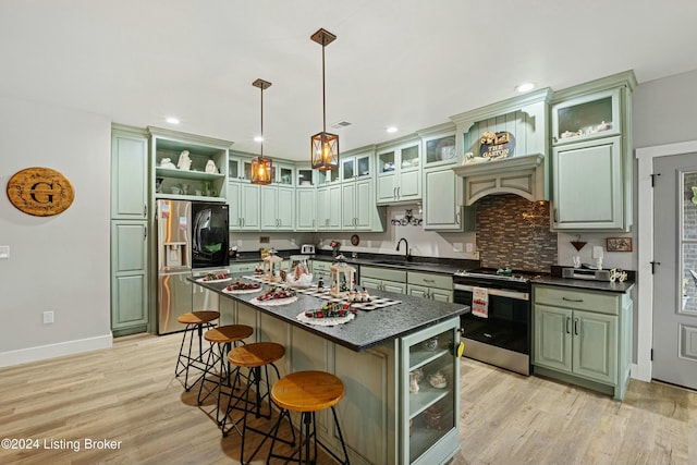 kitchen featuring beverage cooler, dark countertops, appliances with stainless steel finishes, a kitchen island with sink, and green cabinetry