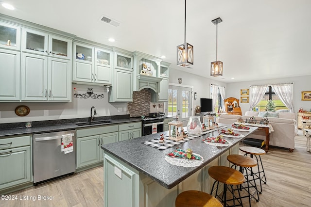 kitchen featuring a sink, green cabinets, open floor plan, and stainless steel dishwasher