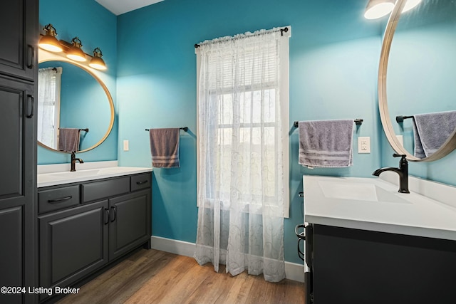 full bathroom featuring baseboards, two vanities, a sink, and wood finished floors