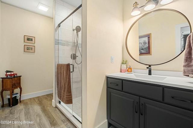 full bathroom featuring wood finished floors, a shower stall, vanity, and baseboards