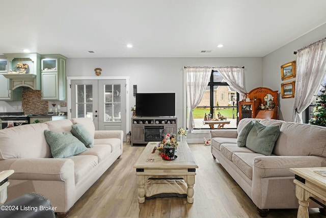 living area with light wood-type flooring, french doors, a fireplace, and recessed lighting