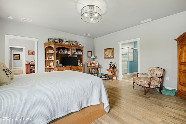 bedroom with baseboards, an inviting chandelier, visible vents, and light wood-style floors