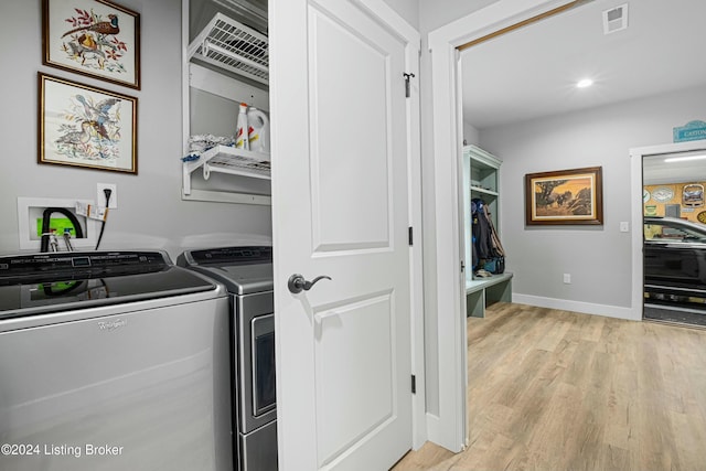 laundry room with light wood finished floors, washing machine and clothes dryer, visible vents, laundry area, and baseboards