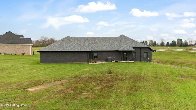 back of house featuring a shingled roof, a yard, and central AC unit