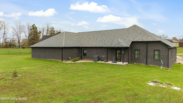 rear view of house with roof with shingles, fence, a yard, central air condition unit, and brick siding