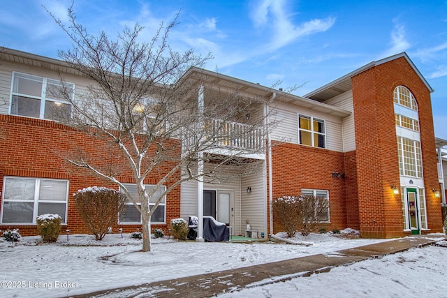 snow covered house featuring a balcony