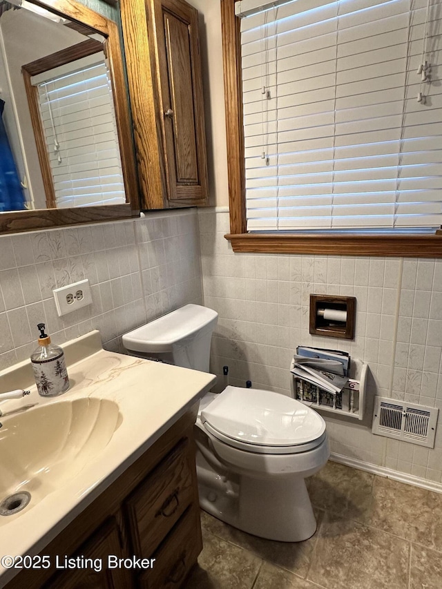 bathroom featuring vanity, tile walls, and toilet