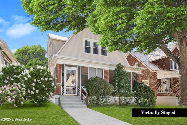 view of front of home featuring brick siding, a gambrel roof, and a front lawn