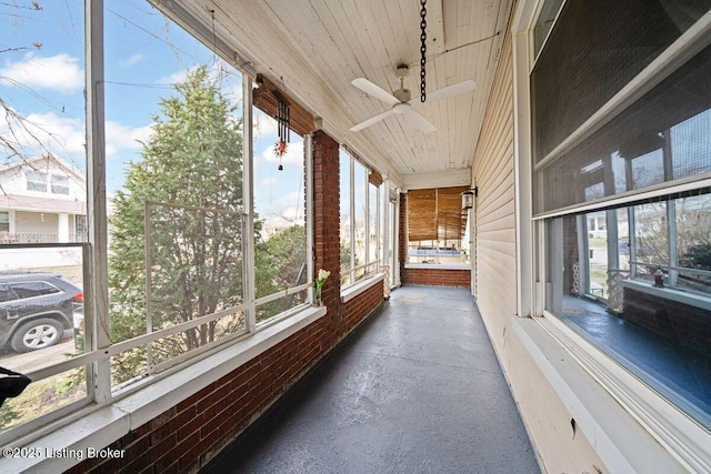 unfurnished sunroom with a wealth of natural light, wood ceiling, and a ceiling fan