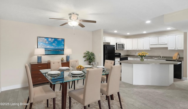 dining space featuring ceiling fan, sink, and light carpet