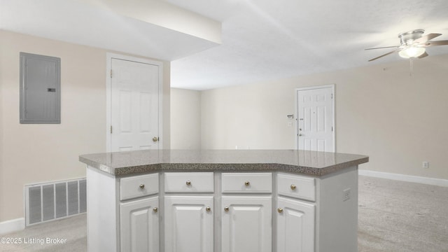 kitchen with electric panel, white cabinetry, and a kitchen island