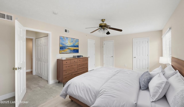 carpeted bedroom featuring ceiling fan and two closets