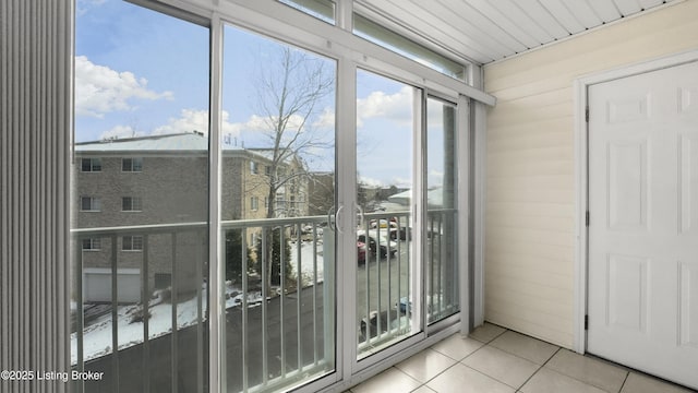 doorway featuring light tile patterned flooring and wood walls