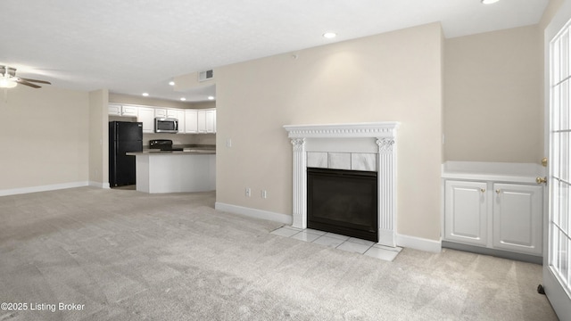 unfurnished living room with a fireplace, light carpet, and ceiling fan