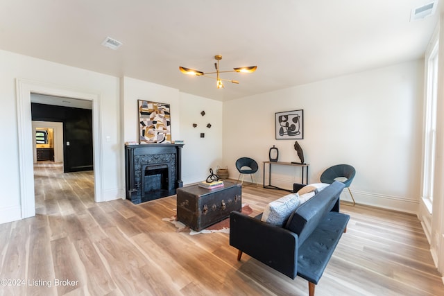 living area featuring a fireplace with flush hearth, visible vents, baseboards, and wood finished floors