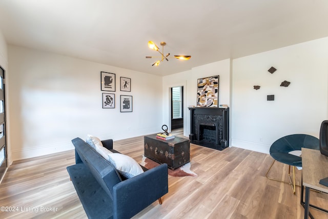 living room with light wood-style floors, a fireplace with flush hearth, baseboards, and a notable chandelier