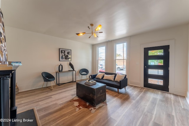 living area with light wood-style flooring, a chandelier, and baseboards