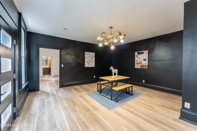 dining area featuring an accent wall, visible vents, a notable chandelier, and light wood-style flooring