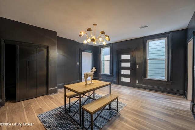 dining area with light wood finished floors, visible vents, and an inviting chandelier