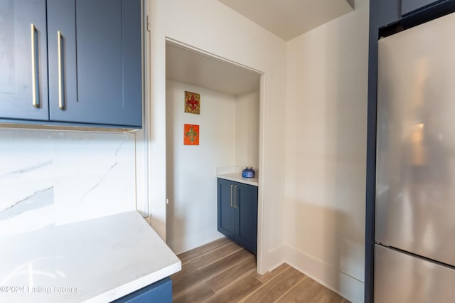 kitchen with light countertops, dark wood-style flooring, freestanding refrigerator, and blue cabinets