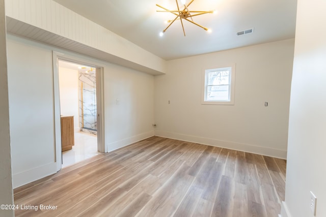 unfurnished room featuring light wood-style floors, baseboards, visible vents, and a chandelier