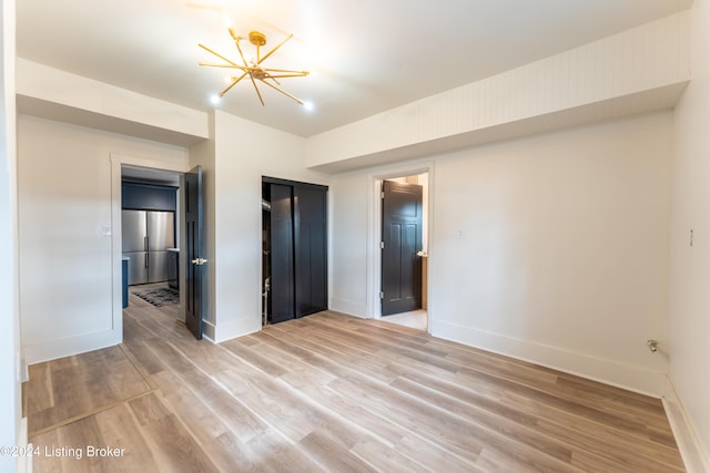 unfurnished bedroom with light wood finished floors, baseboards, and a chandelier