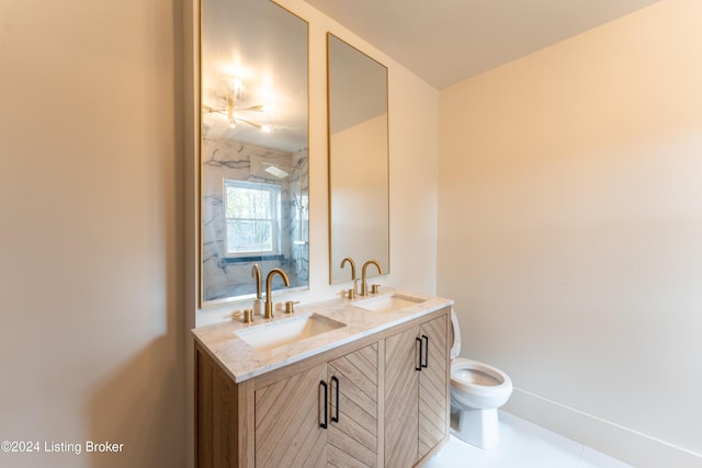 full bath featuring toilet, double vanity, baseboards, and a sink