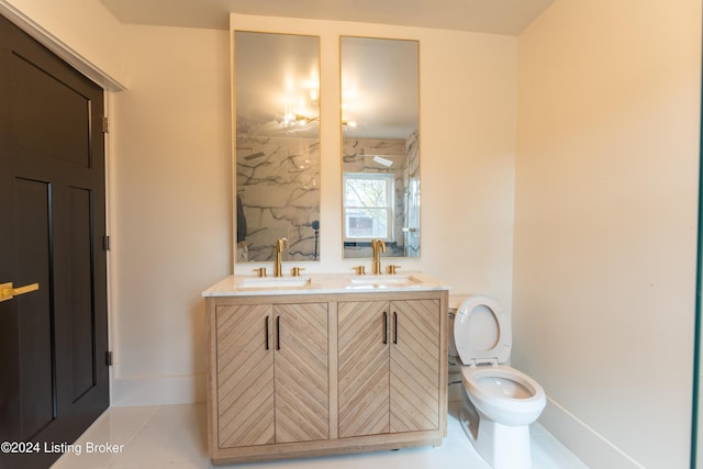 full bathroom with double vanity, a sink, toilet, and baseboards