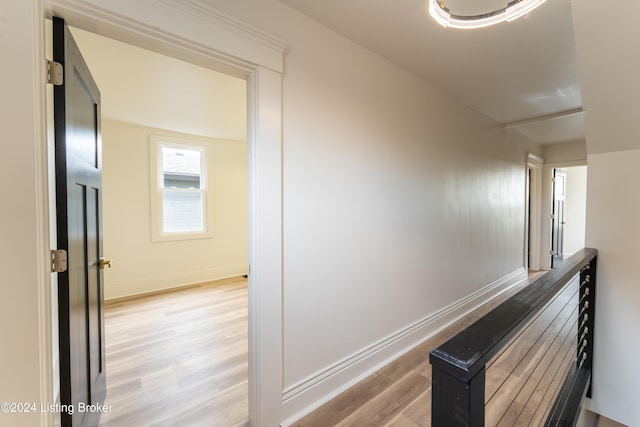 corridor with light wood-type flooring, baseboards, and an upstairs landing