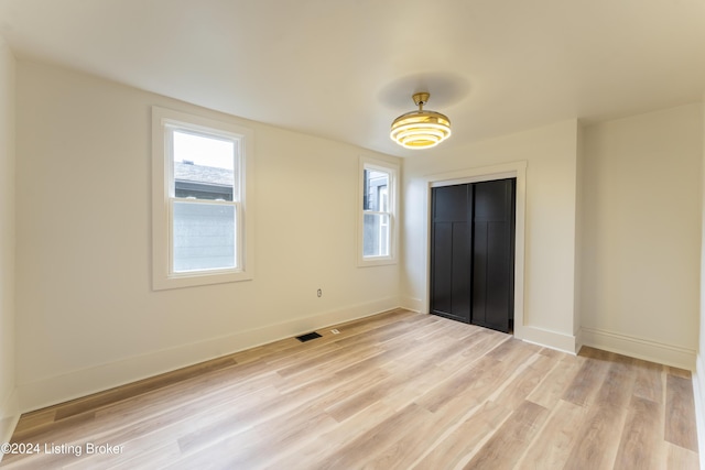 unfurnished bedroom with a closet, light wood-style flooring, and baseboards