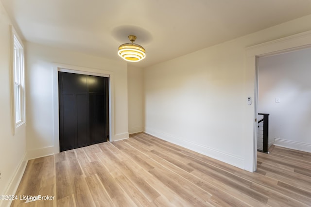 unfurnished bedroom with a closet, light wood-style flooring, and baseboards