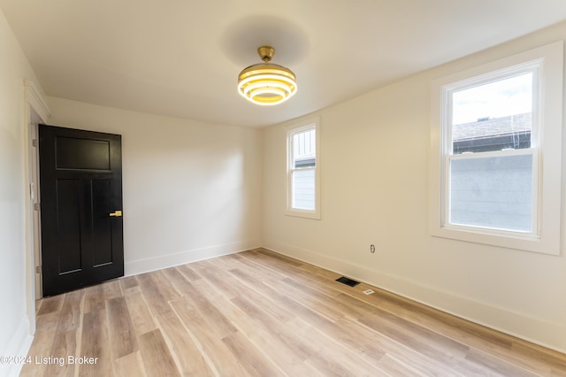 spare room featuring a healthy amount of sunlight, light wood-style floors, baseboards, and visible vents