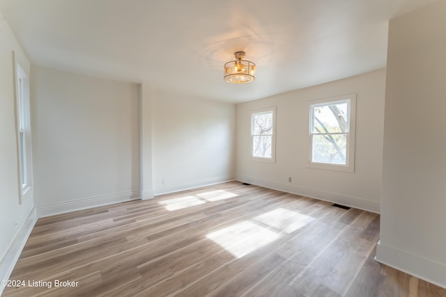 empty room with baseboards, visible vents, and light wood finished floors