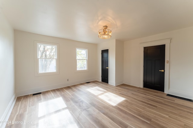 empty room with light wood finished floors, baseboards, and visible vents