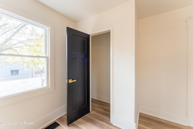 interior space featuring light wood-type flooring, multiple windows, and baseboards