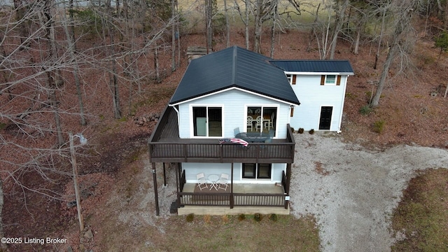 view of front of home featuring dirt driveway, metal roof, and a wooden deck