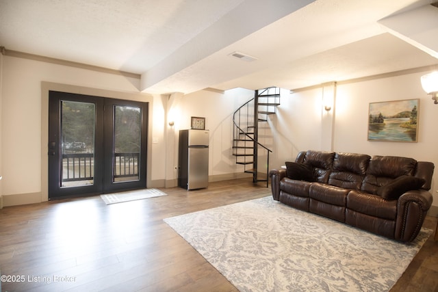 living area featuring baseboards, visible vents, stairway, and light wood finished floors