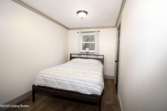 bedroom featuring a textured ceiling, dark wood-type flooring, ornamental molding, and baseboards