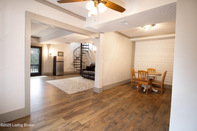 dining space featuring a textured ceiling, wood finished floors, stairs, and baseboards