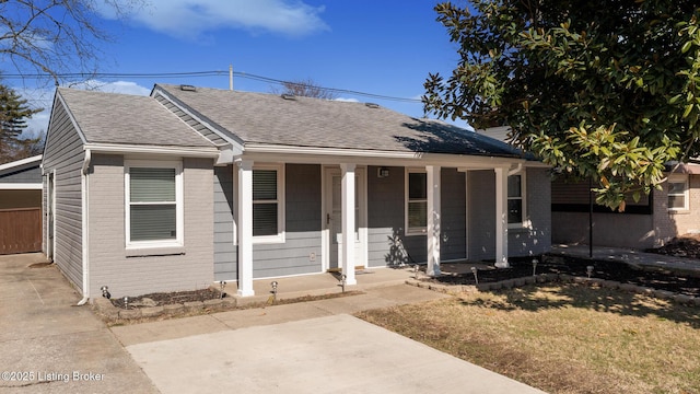 bungalow-style home with covered porch, brick siding, and roof with shingles