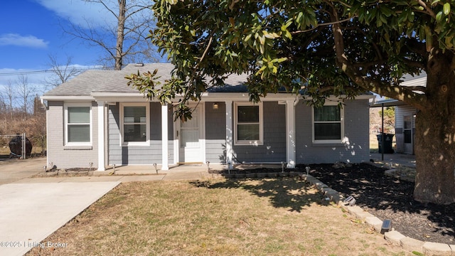 view of front facade with a front yard, brick siding, and roof with shingles