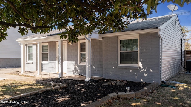 bungalow featuring a porch, brick siding, and roof with shingles