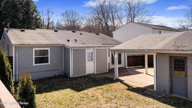 rear view of property with a shingled roof, a lawn, and a patio